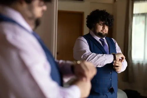 Retrato de novio ajustando su traje con un estilo cinematográfico. Fotografía profesional de preparación de boda por David Sánchez.