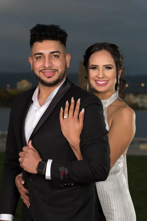  Pareja de novios posando juntos con un fondo iluminado. Fotografía de boda con estilo formal y elegante por David Sánchez.