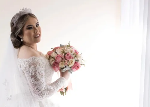  Novia sosteniendo un ramo, con luz natural entrando por una ventana. Retrato elegante de novia por David Sánchez.